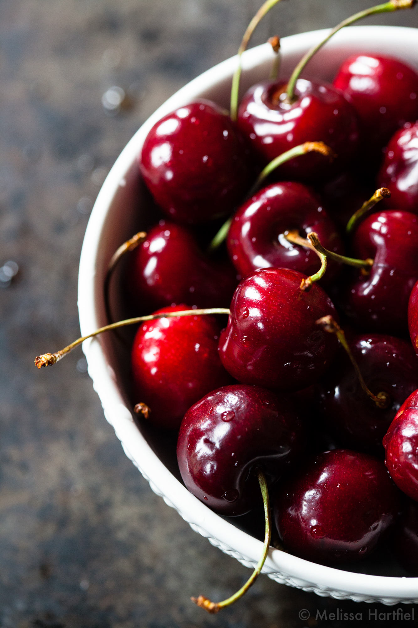 a bowl full of ripe cherries with water droplets